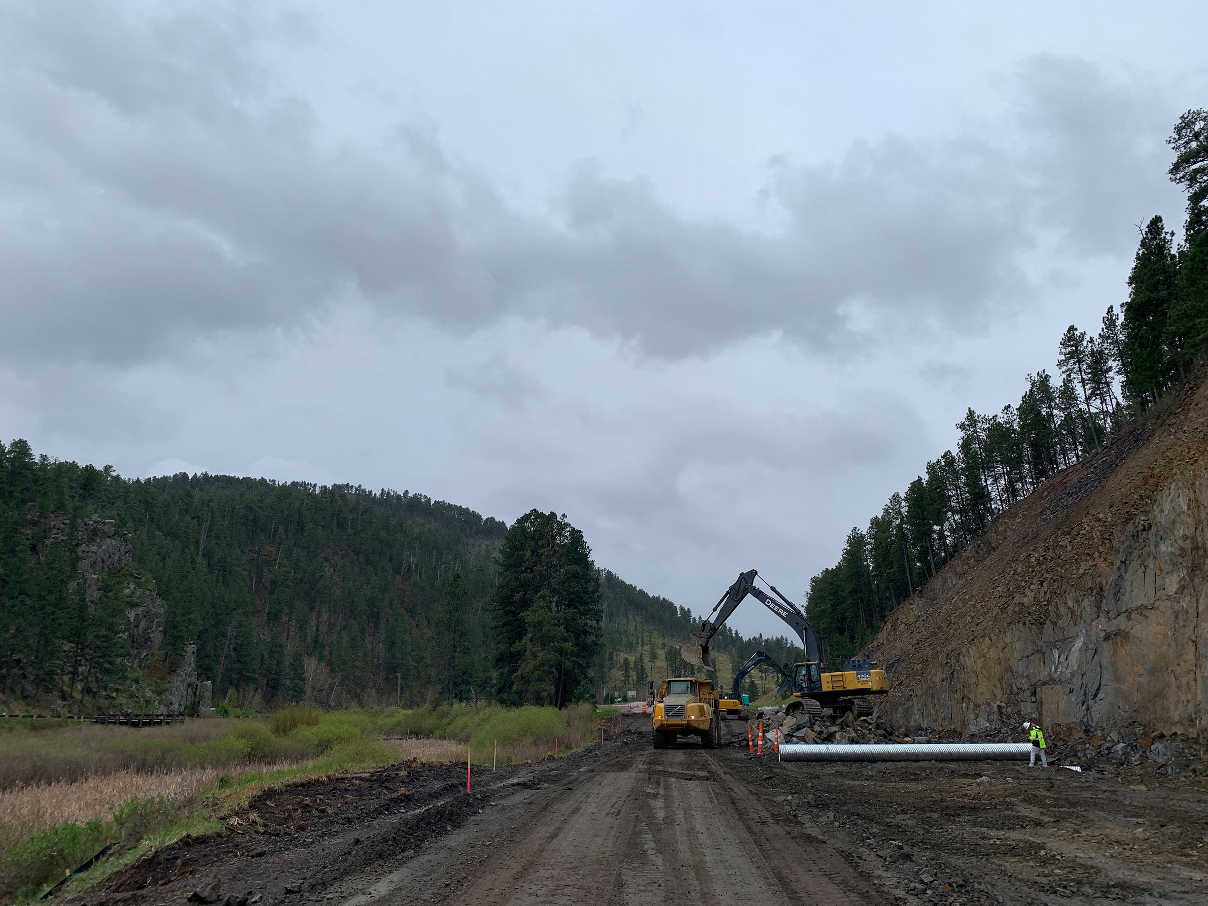 Construction workers working on pipe in ground.